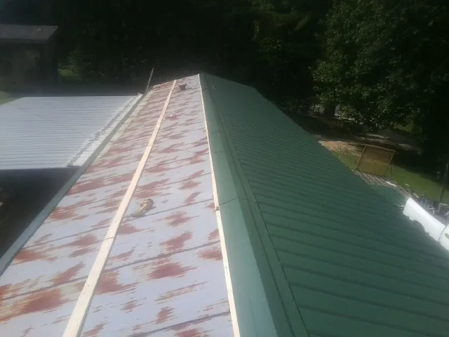Old rusted panels beside newly installed green metal roofing — Wind Damage Roof Repair by Roofing Brothers in North Salem