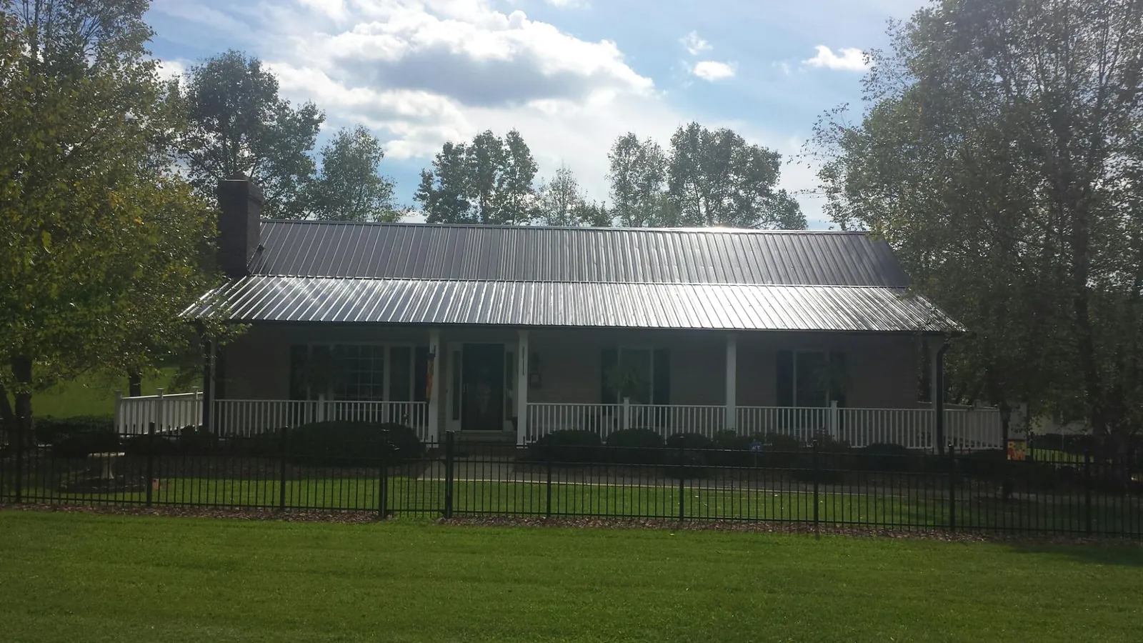 Gray metal roof on a brick ranch with a full width front porch — Gutter Guard Installation work by our crew in North Salem